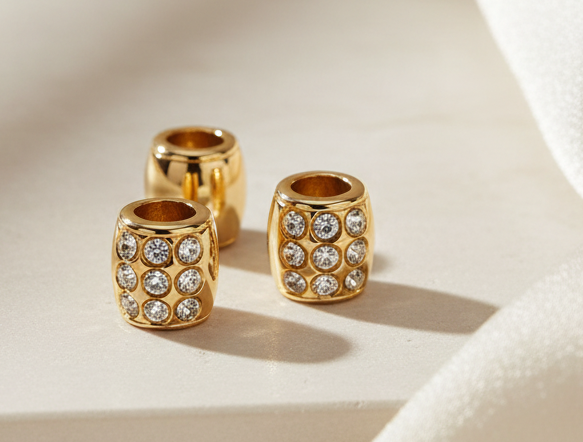 Three small gold crystal barrel loc beads styled on cream stone and silk