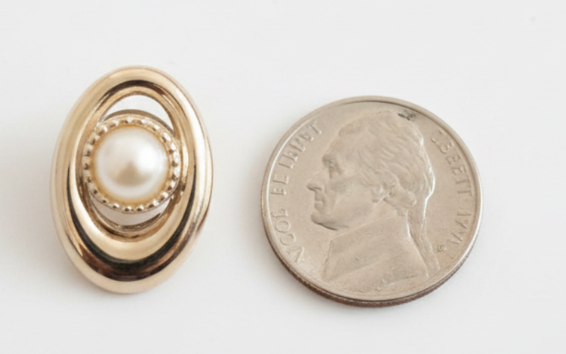 Pearl loc charm front beside a nickel on a white background
